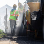 Worker raking ground to prepare for asphalt paving