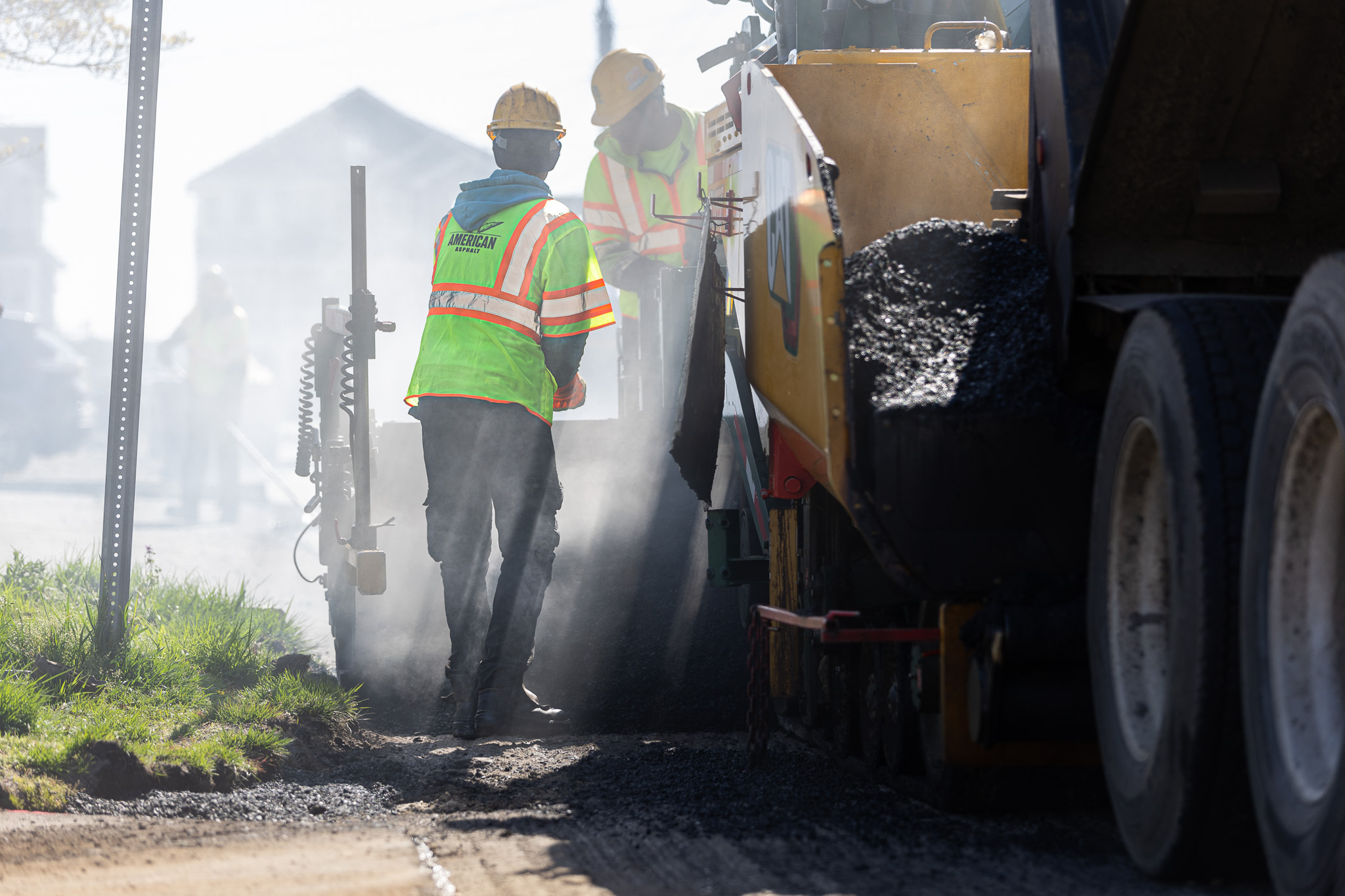 Worker raking ground to prepare for asphalt paving